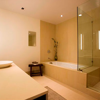 A contemporary bathroom with a minimalist design, featuring a bathtub, glass shower enclosure, vessel sink, and soft ambient lighting by Tycon Builders Inc.
